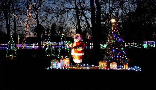 A festive scene featuring a lit Christmas tree, Santa figure, and colorful gift boxes surrounded by twinkling lights.