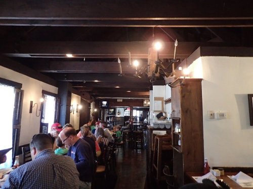 A cozy restaurant interior with wooden beams, tables filled with diners, and a warm, inviting atmosphere.