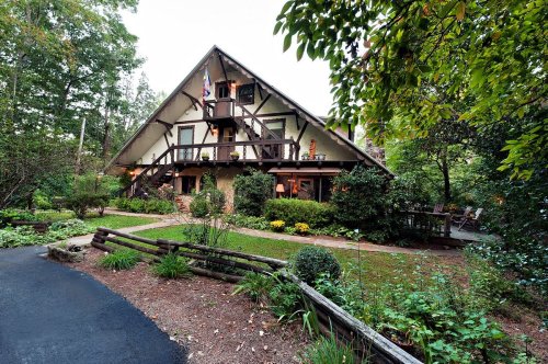 A charming, multi-level house surrounded by lush greenery and a well-kept garden, with a pathway leading to the entrance.