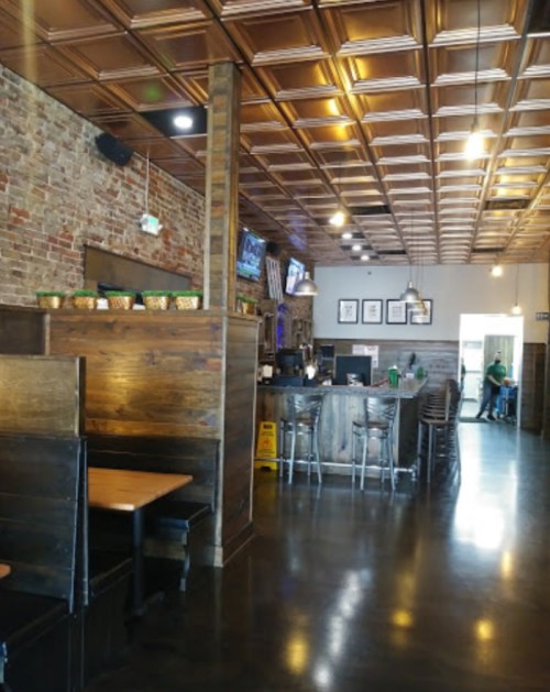 Interior of a restaurant featuring wooden booths, a bar area, and a brick wall with a coffered ceiling.