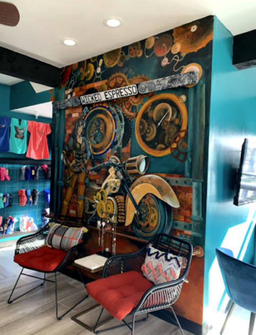 A vibrant mural featuring a motorcycle and gears, with cozy seating in a colorful café setting.