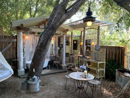 A cozy outdoor seating area with vintage decor, surrounded by trees and soft lighting, creating a charming atmosphere.