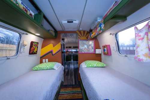 Interior of a colorful camper with two twin beds, vibrant decor, and a cozy, inviting atmosphere.