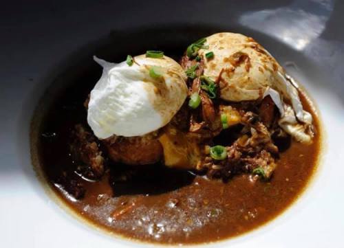 A dish featuring poached eggs on a bed of savory sauce, garnished with green onions.