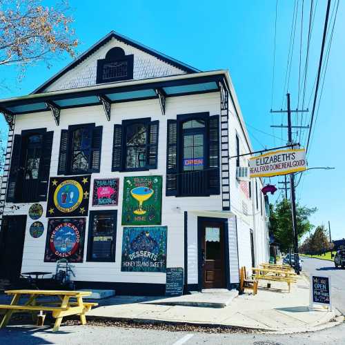 A charming white building with colorful signs, outdoor seating, and a welcoming atmosphere, labeled "Elizabeth's."