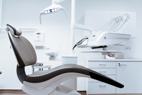 A modern dental office featuring a dental chair, overhead light, and dental equipment in a clean, bright environment.