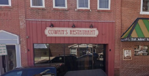 Exterior of Cowan's Restaurant, featuring a red facade and vintage signage, located in a brick building.