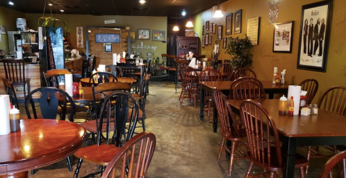 Cozy restaurant interior with wooden tables and chairs, warm lighting, and decor featuring music-themed artwork.