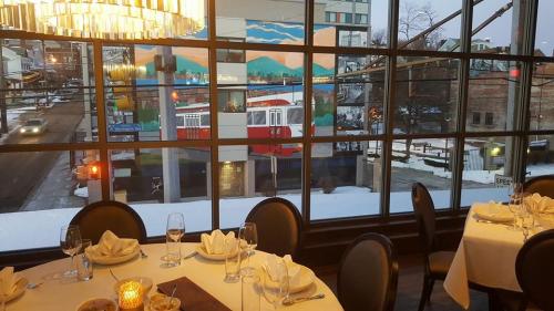 A restaurant interior with elegant table settings, overlooking a snowy street and a colorful mural of a tram.