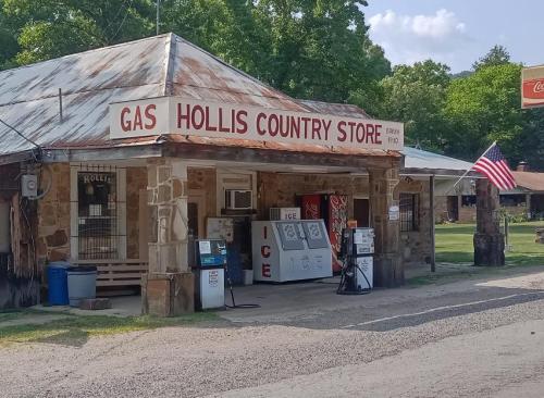 A rustic country store with a gas station, featuring a weathered roof and an American flag outside.