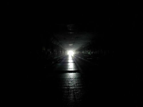 A dark tunnel with a bright light at the far end, illuminating the path ahead.