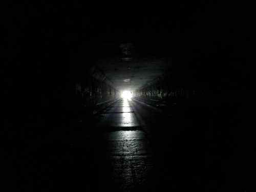 A dark tunnel with a bright light at the far end, illuminating the path ahead.