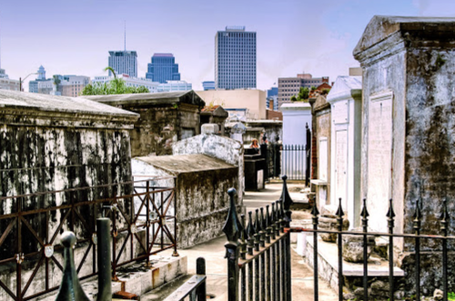 A historic cemetery with tombs and a city skyline in the background, showcasing a blend of architecture.