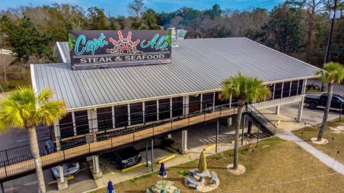 Aerial view of Capt. Al's Steak & Seafood restaurant with a metal roof and palm trees in the foreground.