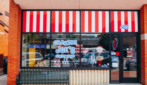 Exterior of Grandpa Joe's Candy Shop, featuring red and white striped awning and colorful window displays.