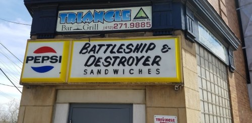 Sign for Triangle Bar & Grill featuring "Battleship & Destroyer Sandwiches" and a Pepsi logo.