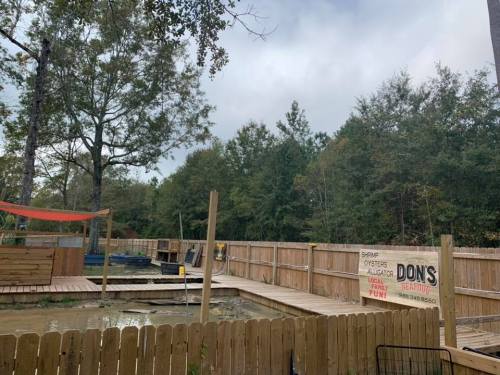A wooden deck area with a sign reading "Don's" surrounded by trees and a cloudy sky.