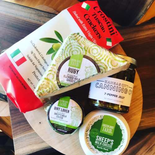 A wooden platter featuring cheese, crackers, and pepper jelly, showcasing a variety of gourmet snacks.