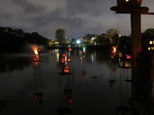 A serene night scene with glowing jack-o'-lanterns floating on a dark lake, surrounded by trees and soft lights.