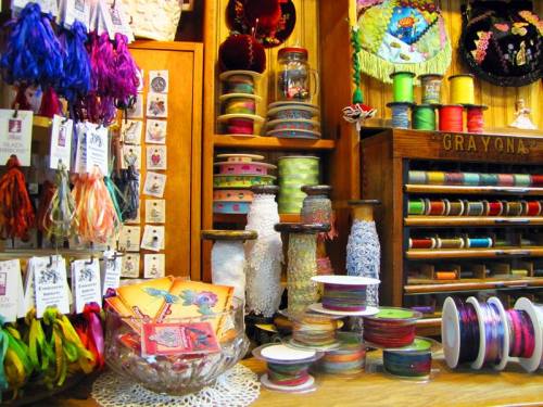 A colorful display of ribbons, threads, and embellishments in a craft store, showcasing various textures and hues.
