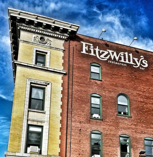 Historic building with a sign for Fitzwilly's restaurant and bar, under a blue sky with scattered clouds.