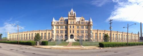 A large, historic building with a castle-like design, featuring turrets and a blue sky in the background.