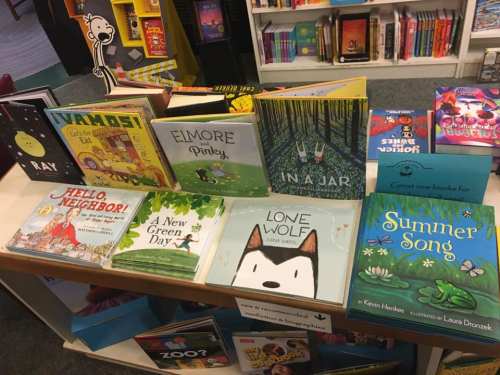 A colorful display of children's books on a table in a bookstore, featuring various titles and illustrations.