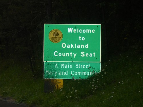Green welcome sign for Oakland County Seat, indicating Main Street in a Maryland community.