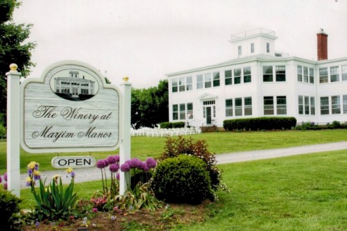Sign for "The Winery at Marjim Manor" with a white building and landscaped garden in the background.