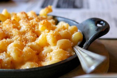 A close-up of creamy macaroni and cheese topped with golden breadcrumbs in a black skillet.