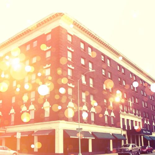 A vintage-style hotel building with a warm, glowing overlay and soft bokeh effects in the background.