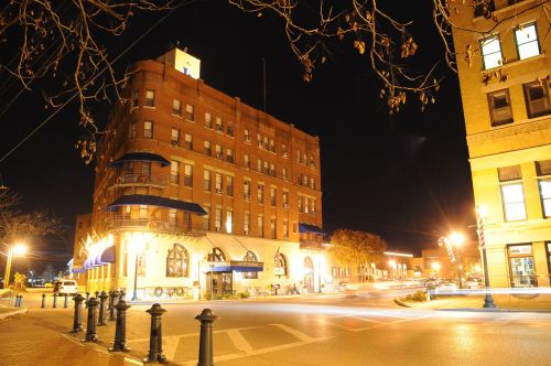 Historic building illuminated at night, featuring architectural details and streetlights in a bustling urban setting.