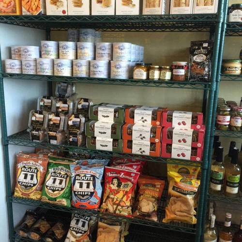 A shelf filled with various snacks, jars, and packaged goods, including chips, cookies, and preserves.