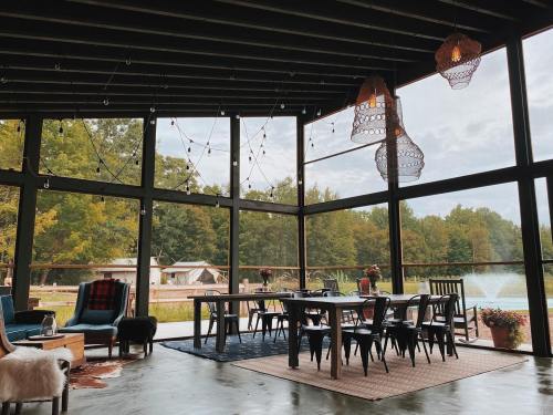 A cozy indoor space with large windows, a dining table, and views of greenery outside. Soft lighting and decor create a warm atmosphere.