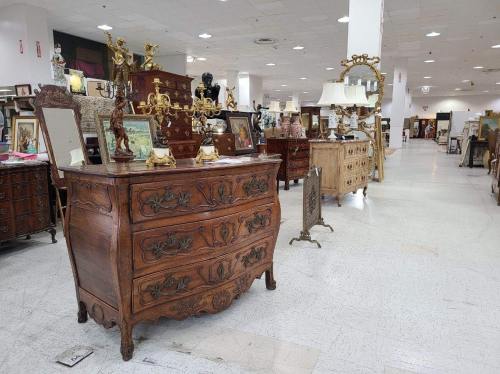 A spacious antique store aisle featuring ornate wooden furniture, including dressers and decorative items.