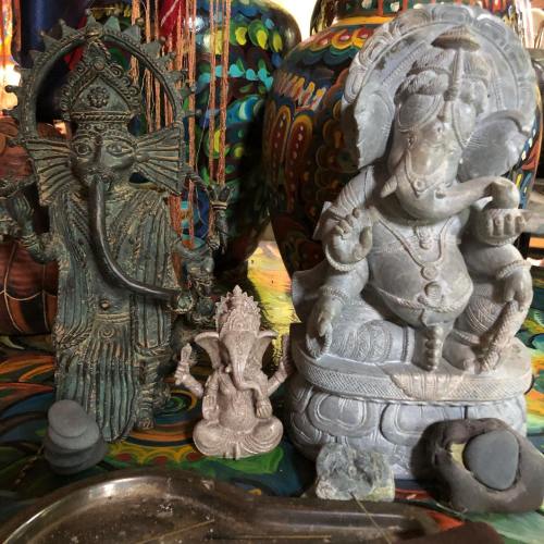 A collection of decorative statues, including two representations of Ganesha, surrounded by colorful pottery.
