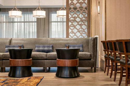 A modern lounge area featuring a gray sofa, wooden accent tables, and stylish lighting fixtures.