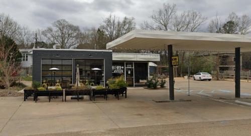 A modern café with large windows and outdoor seating, set in a quiet area with a car parked nearby.