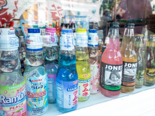 A colorful display of various Ramune soda bottles and Jones soda in a shop window.
