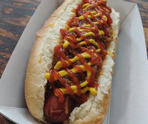 A hot dog in a bun topped with ketchup and mustard, served in a cardboard tray.
