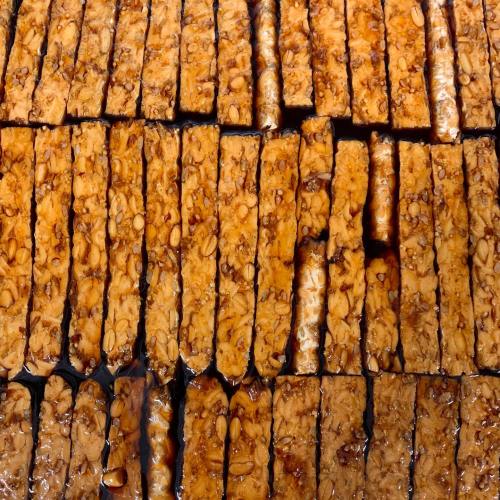 Rows of golden-brown tempeh slices arranged neatly, showcasing a glossy, caramelized surface.