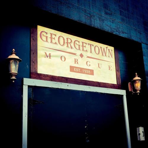 Sign for Georgetown Morgue, established in 1928, with decorative lanterns on either side of the entrance.