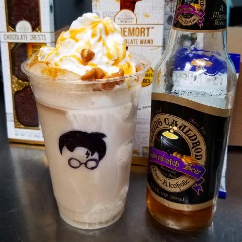 A frosty drink topped with whipped cream and caramel, featuring a Harry Potter-themed design, alongside a bottle of butterscotch beer.