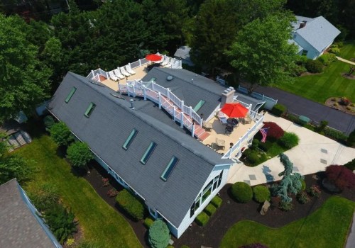Aerial view of a house with a rooftop deck, surrounded by greenery and landscaped gardens.