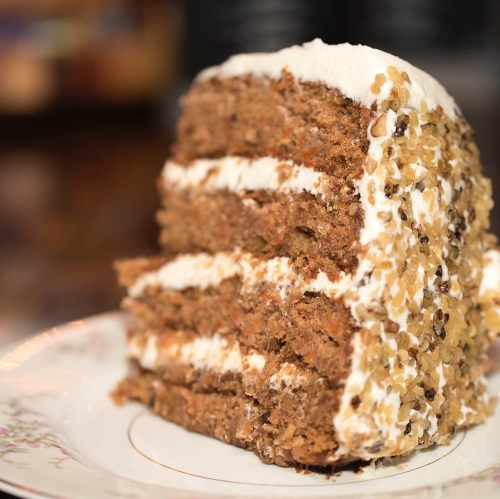 A slice of layered cake with cream filling and a textured, golden-brown exterior on a decorative plate.
