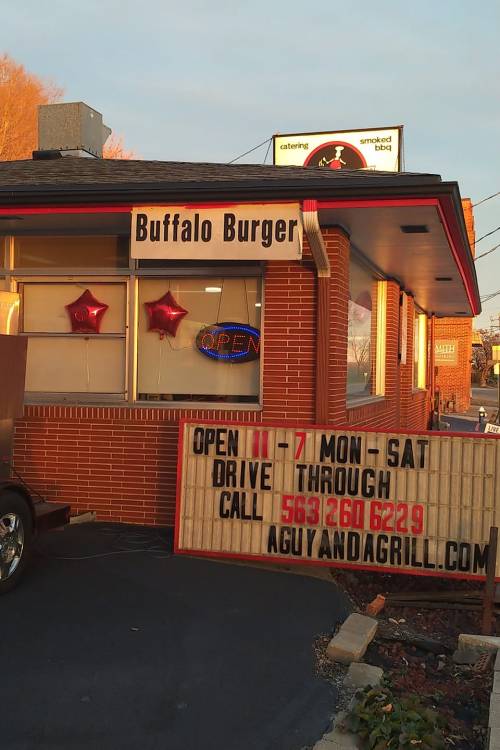 A restaurant exterior featuring a sign for "Buffalo Burger," with balloons and a drive-thru announcement.