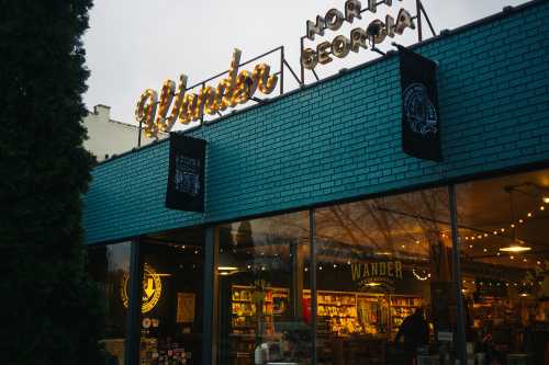 A storefront with a blue exterior and a "Wander" sign, featuring large windows and decorative lights.