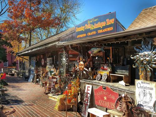 A charming antique shop with various crafts and treasures displayed outside, surrounded by autumn foliage.
