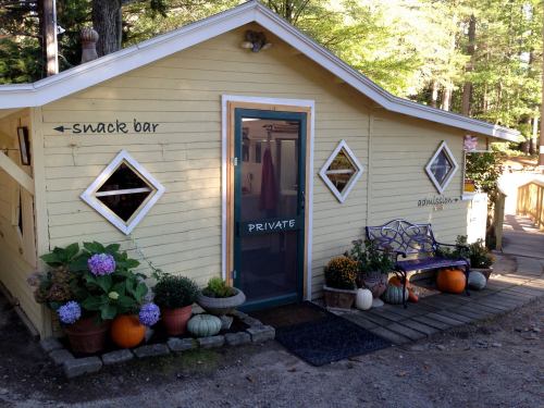 A yellow building with diamond windows, labeled "snack bar" and "private," surrounded by plants and pumpkins.