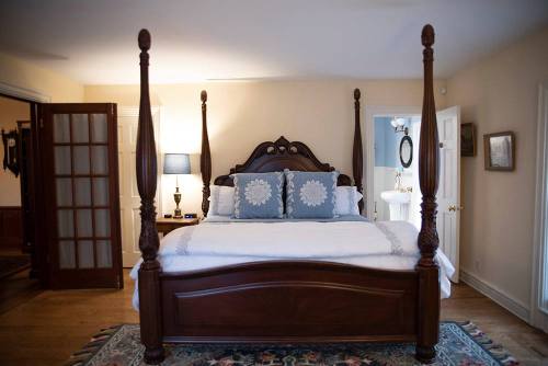 A cozy bedroom featuring a four-poster bed with decorative pillows and warm lighting.